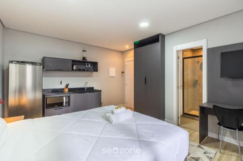 a large white bed in a room with a kitchen at TCO - Apartamentos no Centro Histórico Porto Alegre/RS in Porto Alegre