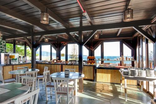 a restaurant with tables and chairs and windows at Pousada do Arvoredo in Bombinhas