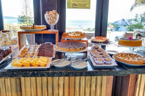 a buffet with many different types of cakes and pastries at Pousada do Arvoredo in Bombinhas