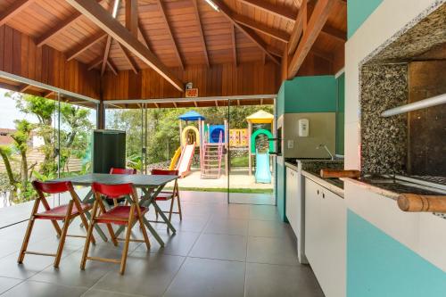 a kitchen with a table and chairs and a playground at Pousada do Arvoredo in Bombinhas