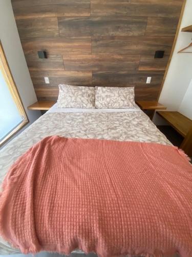 a bedroom with a bed with a red blanket on it at M House Pichilemu in Pichilemu