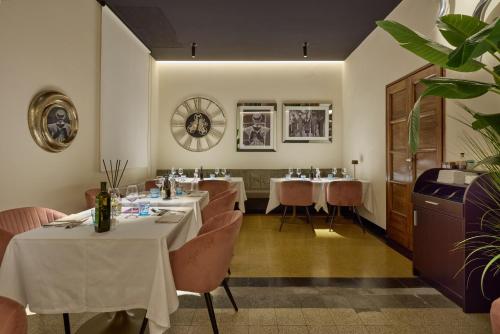 a restaurant with white tables and chairs and plants at Le Maginot Relais in Castelvetro Piacentino