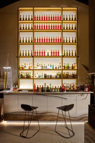 a bar with two chairs in front of a shelf with bottles at Le Maginot Relais in Castelvetro Piacentino