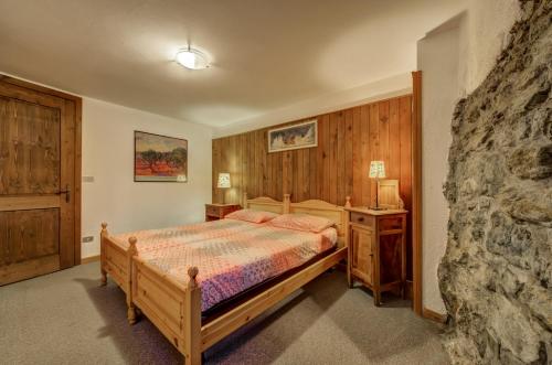 a bedroom with a bed and a stone wall at Alpine Essence, typical mountain style apartment CIR AYAS0036 in Champoluc