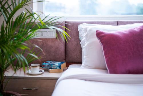 a bed with a pink pillow and a cup of coffee at Hotel Sagar Residency - Best Mountain View Hotel in Palampur in Pālampur