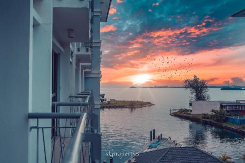 a view of the water from a balcony with a sunset at Seaview Suites at Admiral Bay in Port Dickson