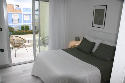 a white bedroom with a bed and a balcony at Casa Janna in Cabo Roig