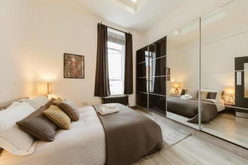 a bedroom with a large bed and a mirror at Amazing warehouse conversion apartment in Chiswick in London