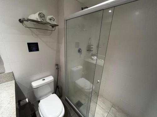 a bathroom with a toilet and a glass shower at Flat 807 confortável no Centro de Três Rios in Três Rios