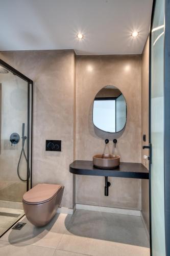 a bathroom with a sink and a toilet and a mirror at Anima Deluxe Suites in Nafplio