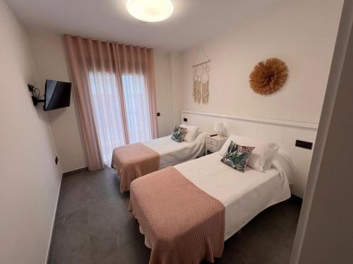 a hotel room with two beds and a television at Apartamentos Granada 76 in Nerja