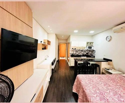 a room with a bed and a television and a kitchen at STUDIO - ao lado do batel in Curitiba