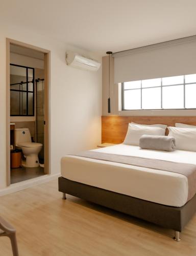 a bedroom with a large bed and a bathroom at Fence by Bernalo Hotels in Medellín
