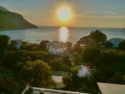 a sunset over the ocean with houses and trees at Alkyonis Apartments in Panormos Kalymnos