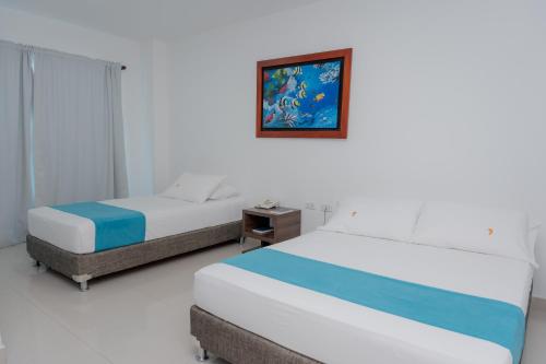 a bedroom with two beds and a picture on the wall at Hotel Aguamarina in Santa Marta