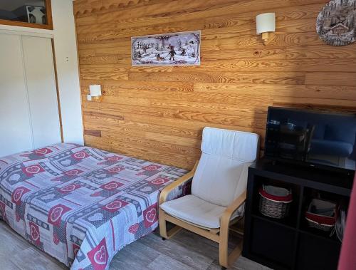 a bedroom with a bed and a chair and a television at Appartement 6 personnes au pied des pistes - Ecrin des Neiges 205 in Valmeinier