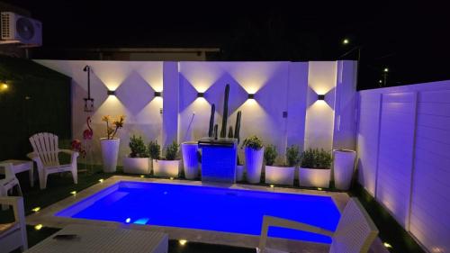 a swimming pool lit up at night with purple lights at Jazmin's Apartment in Oranjestad