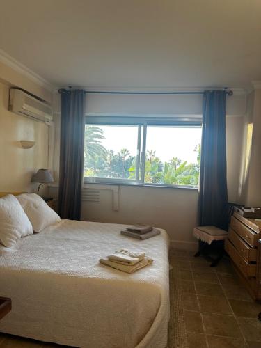 une chambre avec un lit et une grande fenêtre dans l'établissement CHARMANT STUDIO AVEC PISCINE à LA MIRANDOLE, à Vallauris