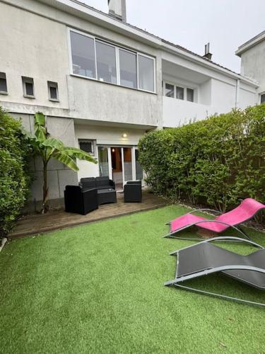 a house with a yard with pink items on the grass at Appart bain à remous et jardin proche plage l Eden in Calais