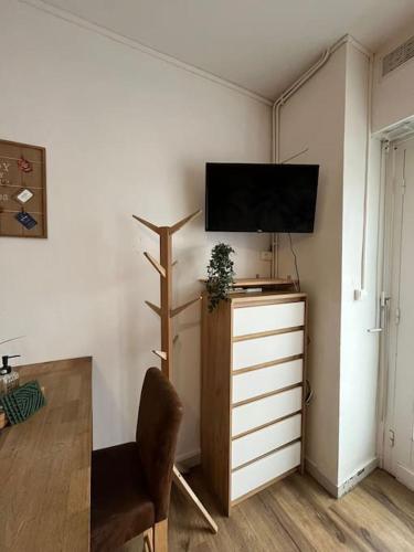 a living room with a tv on top of a dresser at Appart bain à remous et jardin proche plage l Eden in Calais