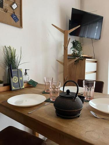 a wooden table with plates and glasses and a tea kettle at Appart bain à remous et jardin proche plage l Eden in Calais