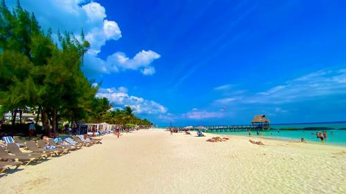 a beach with chairs and people on the sand and a pier at Hotel Turquesa in Playa del Carmen