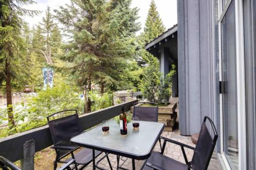 a table on a balcony with two glasses of wine at Cozy Cabin Vibes at Glacier Lodge in Whistler