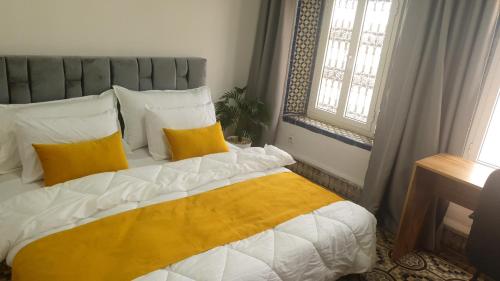 a bedroom with a bed with yellow and white pillows at Riad Apartment with Panoramic Bouregreg & Marina View in Rabat