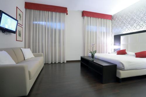 a bedroom with a bed and a couch and a tv at Hotel La Torretta in Bollate