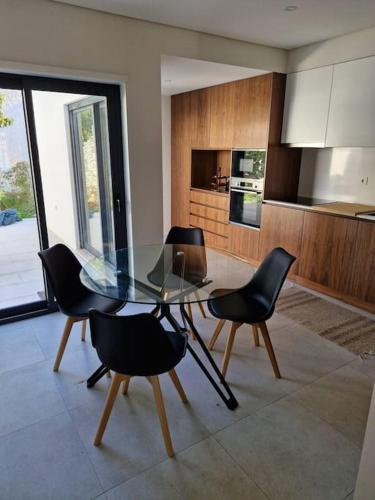 a dining room with a glass table and black chairs at Casa Francisca praia de Mindelo in Mindelo