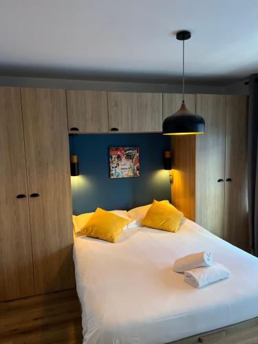 - une chambre avec un grand lit blanc et des oreillers jaunes dans l'établissement Charmant Appartement Antibes, à Antibes