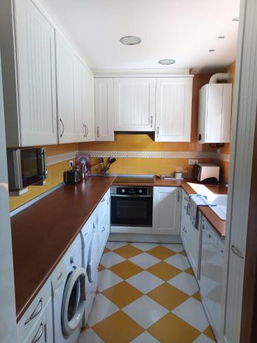 a kitchen with white cabinets and a checkered floor at Casa Carmen in Alcolea de Cinca