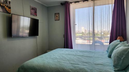 a bedroom with a bed and a tv and a window at Departamentos Amoblados Chileruca in Santiago