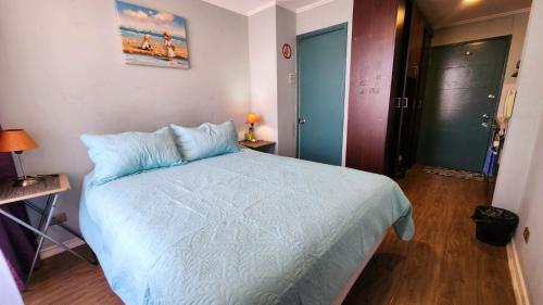 a bedroom with a bed with a blue comforter at Departamentos Amoblados Chileruca in Santiago