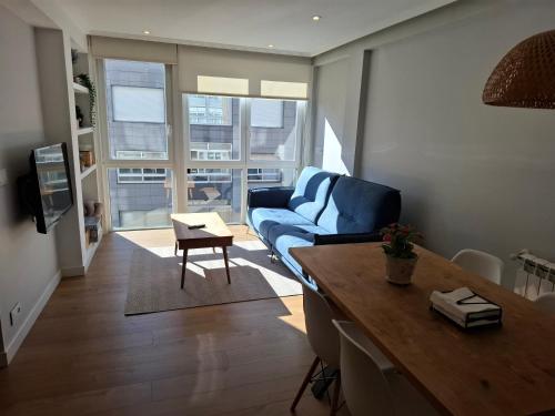 a living room with a blue couch and a table at Apt Moderno céntrico y soleado in Pontevedra