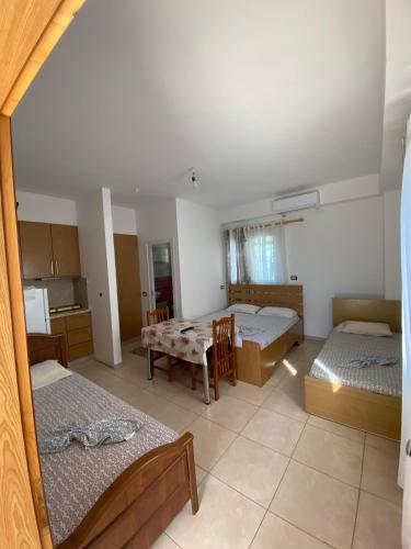 a room with two beds and a table and a kitchen at Eli Apartament's in Lezhë