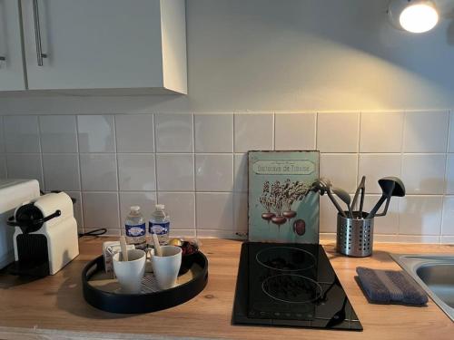 a kitchen counter with a tray with cups on it at La Maison aux volets bleus 37 m3, Bords de Saône in Chalon-sur-Saône