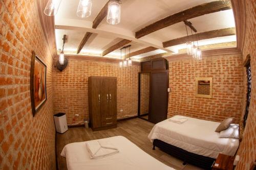 a bedroom with two beds in a room with brick walls at Hot Chipilin in Antigua Guatemala