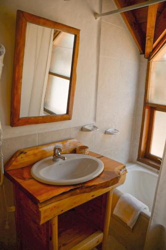 a bathroom with a sink and a mirror and a tub at Lelikelen Cabañas del Bosque in Villa La Angostura