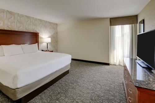 a hotel room with a bed and a flat screen tv at Drury Inn & Suites Charlotte University Place in Charlotte