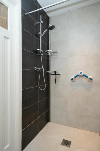 a bathroom with a shower with black tiles at Studio Augusta in Den Burg