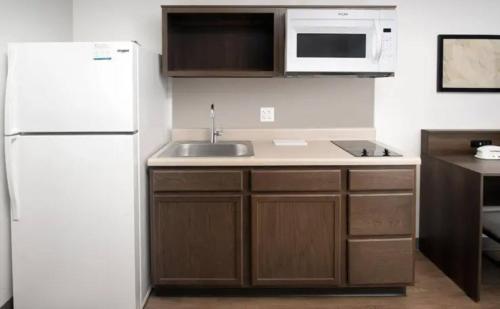 a kitchen with a white refrigerator and a sink at WoodSpring Suites Huntsville - Research Park in Huntsville