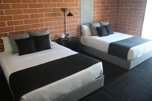 two beds in a room with a brick wall at Ecovergel Santa Lucia in Monterrey