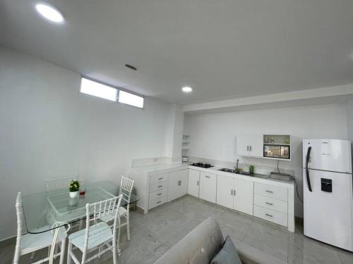 a white kitchen with a table and a refrigerator at Hermoso apartamento #13 piso 3 in Machala
