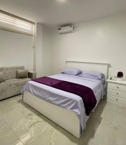 a white bedroom with a bed and a couch at Hermoso apartamento #13 piso 3 in Machala