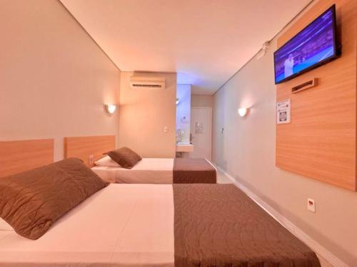 a hotel room with two beds and a flat screen tv at Igaras Hotel in Otacílio Costa