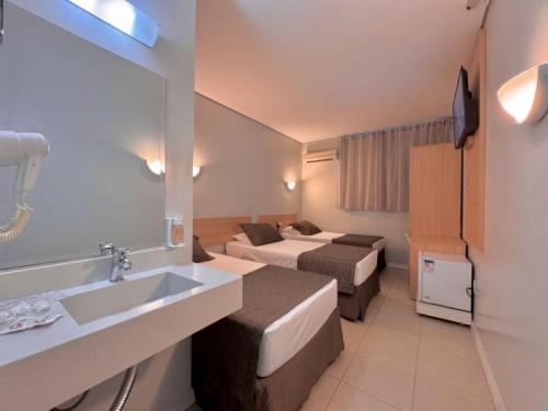 a hotel room with two beds and a sink at Igaras Hotel in Otacílio Costa