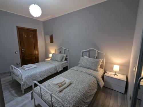 two beds in a small room with two lamps at La casa di Jo in Navacchio