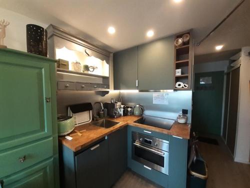 Elle comprend une petite cuisine avec des placards bleus et un évier. dans l'établissement Résidence Melezets 1 - Studio pour 3 Personnes MAE-2001, à Modane