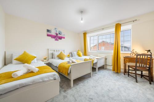 a bedroom with two beds and a desk and a window at Wilkinsons Home-Free parking, Perfect For Contractors & Weekend getaways, Near London City Airport & Excel in London